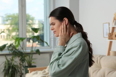 Téléchargez les photos : Young woman suffering from ear pain at home - en image libre de droit
