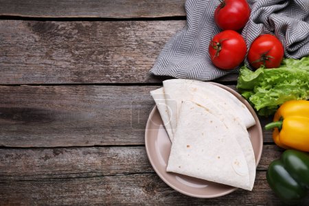 Photo for Delicious folded Armenian lavash and fresh vegetables on wooden table, flat lay. Space for text - Royalty Free Image