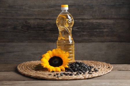 Aceite de girasol, semillas y flor amarilla sobre mesa de madera