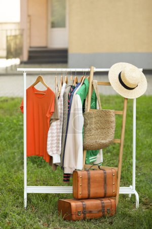 Téléchargez les photos : Clothing rack with different garments in yard. Garage sale - en image libre de droit