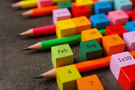 Photo for Many colorful cubes with numbers, multiplications and pencils on dark grey table, closeup - Royalty Free Image