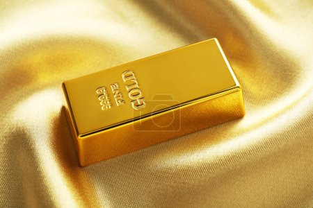 Gold bar on shiny silk fabric, closeup