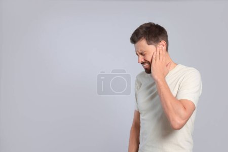 Photo for Man suffering from ear pain on grey background - Royalty Free Image