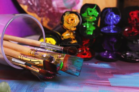Foto de Canvas with colorful abstract painting and different brushes, closeup - Imagen libre de derechos