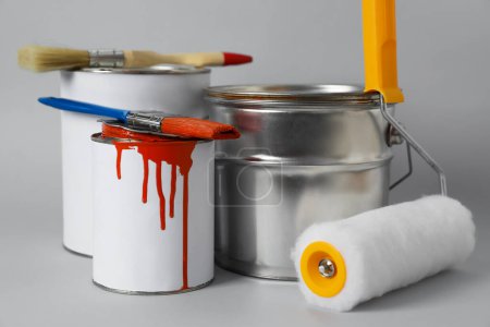 Téléchargez les photos : Cans of orange paint, brushes and roller on grey background - en image libre de droit