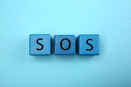 Foto de Abbreviation SOS (Save Our Souls) made of cubes with letters on light blue background, top view - Imagen libre de derechos