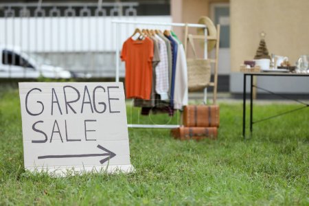 Sign Garage sale written on cardboard in yard