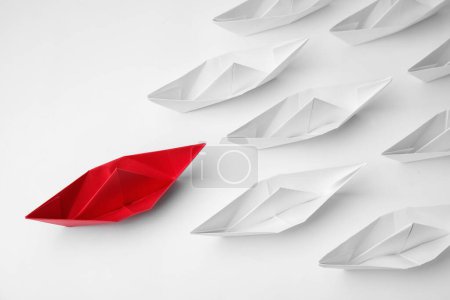 Téléchargez les photos : Group of paper boats following red one on white background, flat lay. Leadership concept - en image libre de droit
