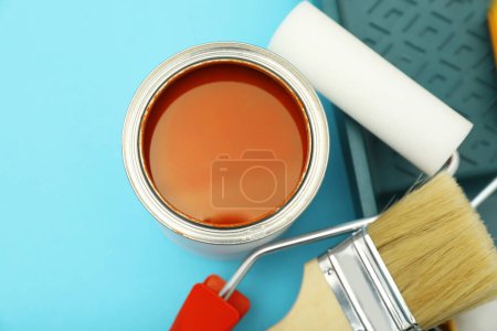 Téléchargez les photos : Can of orange paint, brushes, rollers and container on turquoise background, flat lay - en image libre de droit
