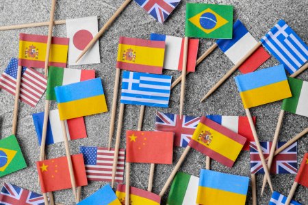 Photo for Many small paper flags of different countries on grey table, flat lay - Royalty Free Image