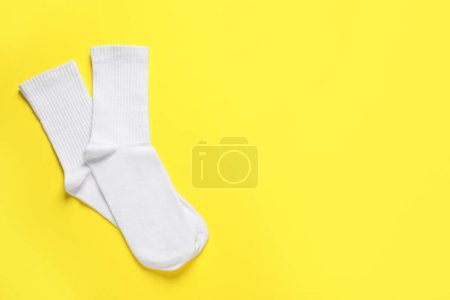 Téléchargez les photos : Pair of white socks on yellow background, flat lay. Space for text - en image libre de droit