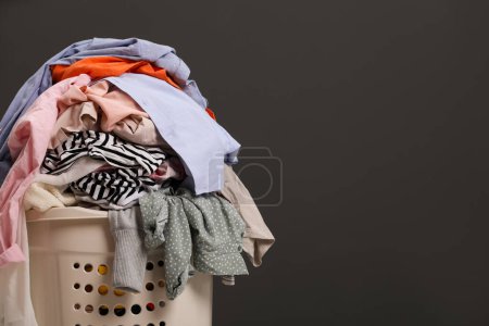 Téléchargez les photos : Laundry basket with clothes against dark grey background. Space for text - en image libre de droit