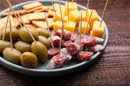 Foto de Toothpick appetizers. Pieces of sausage, olives and cheese on wooden table - Imagen libre de derechos