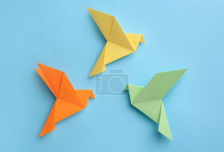 Foto de Origami art. Colorful handmade paper birds on light blue background, flat lay - Imagen libre de derechos