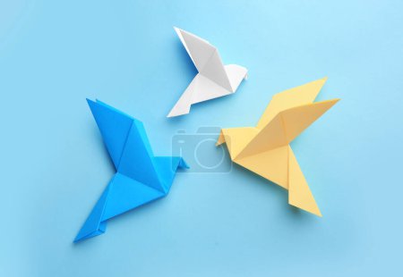 Foto de Origami art. Colorful handmade paper birds on light blue background, flat lay - Imagen libre de derechos