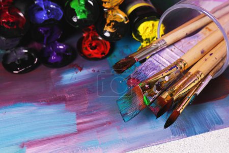 Foto de Canvas with colorful abstract painting and different brushes, closeup - Imagen libre de derechos