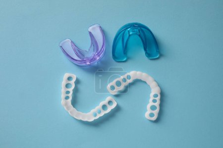 Photo for Different dental mouth guards on light blue background, flat lay. Bite correction - Royalty Free Image