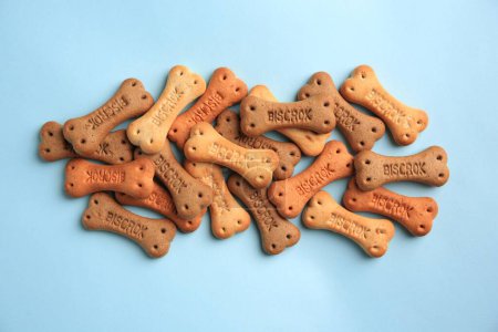 Téléchargez les photos : Bone shaped dog cookies on light blue background, flat lay - en image libre de droit