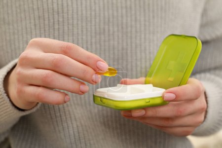 Foto de Woman taking pill from plastic box, closeup of hands - Imagen libre de derechos