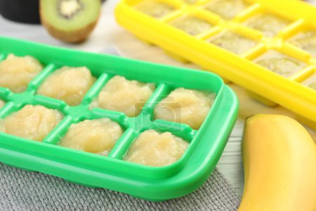 Téléchargez les photos : Banana and kiwi purees in ice cube tray with different fresh fruits white wooden table, closeup - en image libre de droit