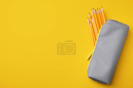 Photo for Many sharp pencils in pencil case on yellow background, top view. Space for text - Royalty Free Image