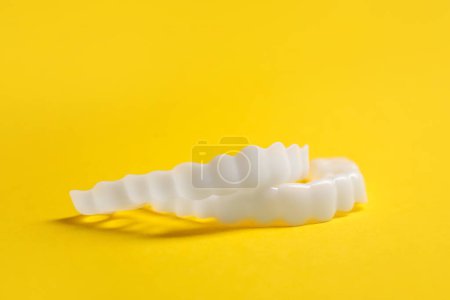 Dental mouth guards on yellow background, closeup. Bite correction