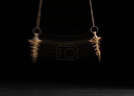 Foto de Hypnosis session. Pendant swinging over surface on black background, motion effect - Imagen libre de derechos