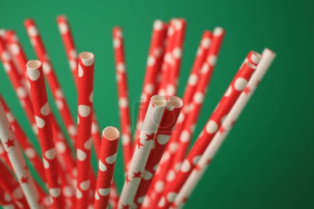 Bright paper drinking straws on green background, closeup