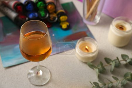 Téléchargez les photos : Glass of tasty wine, colorful paints and canvas, above view. Space for text - en image libre de droit