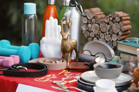 Téléchargez les photos : Many different items on red tablecloth outdoors. Garage sale - en image libre de droit
