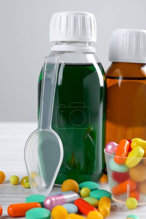 Téléchargez les photos : Bottles of syrups with pills on wooden table against white background, closeup. Cough and cold medicine - en image libre de droit