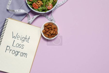 Téléchargez les photos : Notebook with phrase Weight Loss Program, bowl of salad and almonds on pink background, flat lay. Space for text - en image libre de droit