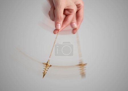 Photo for Hypnosis session. Woman swinging pendant on light background, closeup. Motion effect - Royalty Free Image
