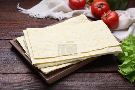 Photo for Delicious folded Armenian lavash and fresh vegetables on wooden table, closeup - Royalty Free Image