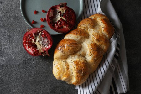 Téléchargez les photos : Homemade braided bread and pomegranate on grey table, flat lay. Cooking traditional Shabbat challah - en image libre de droit