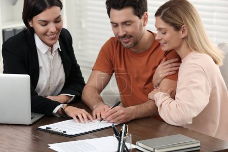 Photo for Professional notary helping couple with paperwork in office - Royalty Free Image