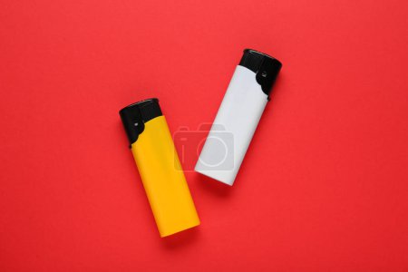 Téléchargez les photos : Stylish small pocket lighters on red background, flat lay - en image libre de droit