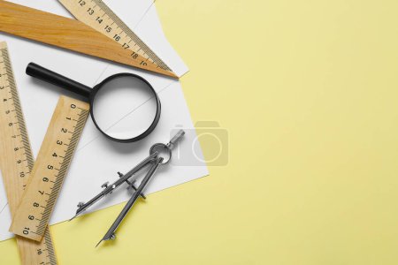 Photo for Different rulers, magnifying glass and compass on yellow background, flat lay. Space for text - Royalty Free Image