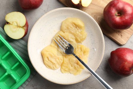 Foto de Apple puree in plate and fresh apple fruits on grey table, flat lay - Imagen libre de derechos