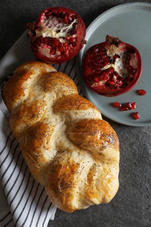 Téléchargez les photos : Homemade braided bread and pomegranate on grey table, flat lay. Cooking traditional Shabbat challah - en image libre de droit