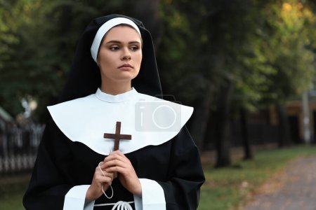 Téléchargez les photos : Young nun with Christian cross in park outdoors, space for text - en image libre de droit