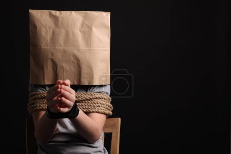 Photo for Little boy in paper bag tied up and taken hostage on dark background. Space for text - Royalty Free Image