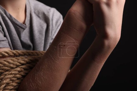 Photo for Little boy tied up and taken hostage on dark background, closeup - Royalty Free Image