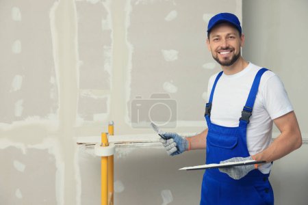 Photo for Professional worker with putty knives near wall. Space for text - Royalty Free Image