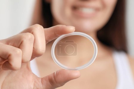Téléchargez les photos : Woman holding diaphragm vaginal contraceptive ring on blurred background, closeup - en image libre de droit