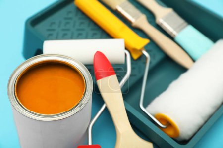 Téléchargez les photos : Can of orange paint, brushes, rollers and container on turquoise background, closeup - en image libre de droit