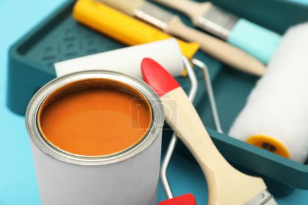 Téléchargez les photos : Can of orange paint, brushes, rollers and container on turquoise background, closeup - en image libre de droit