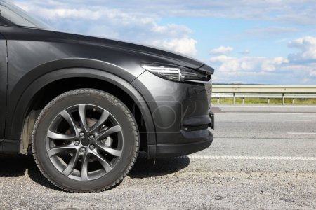 Foto de Nuevo coche moderno negro en la carretera de asfalto, primer plano. Espacio para texto - Imagen libre de derechos