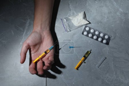 Foto de Man with syringe on grey marble table, top view. Drug addiction - Imagen libre de derechos