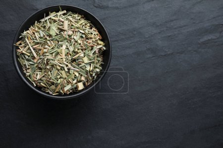 Téléchargez les photos : Bowl with aromatic dried lemongrass on black table, top view. Space for text - en image libre de droit